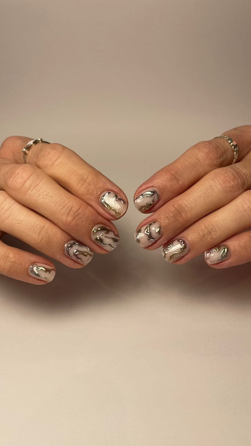 Ongles courts nude avec reliefs métallisés dorés et argentés.