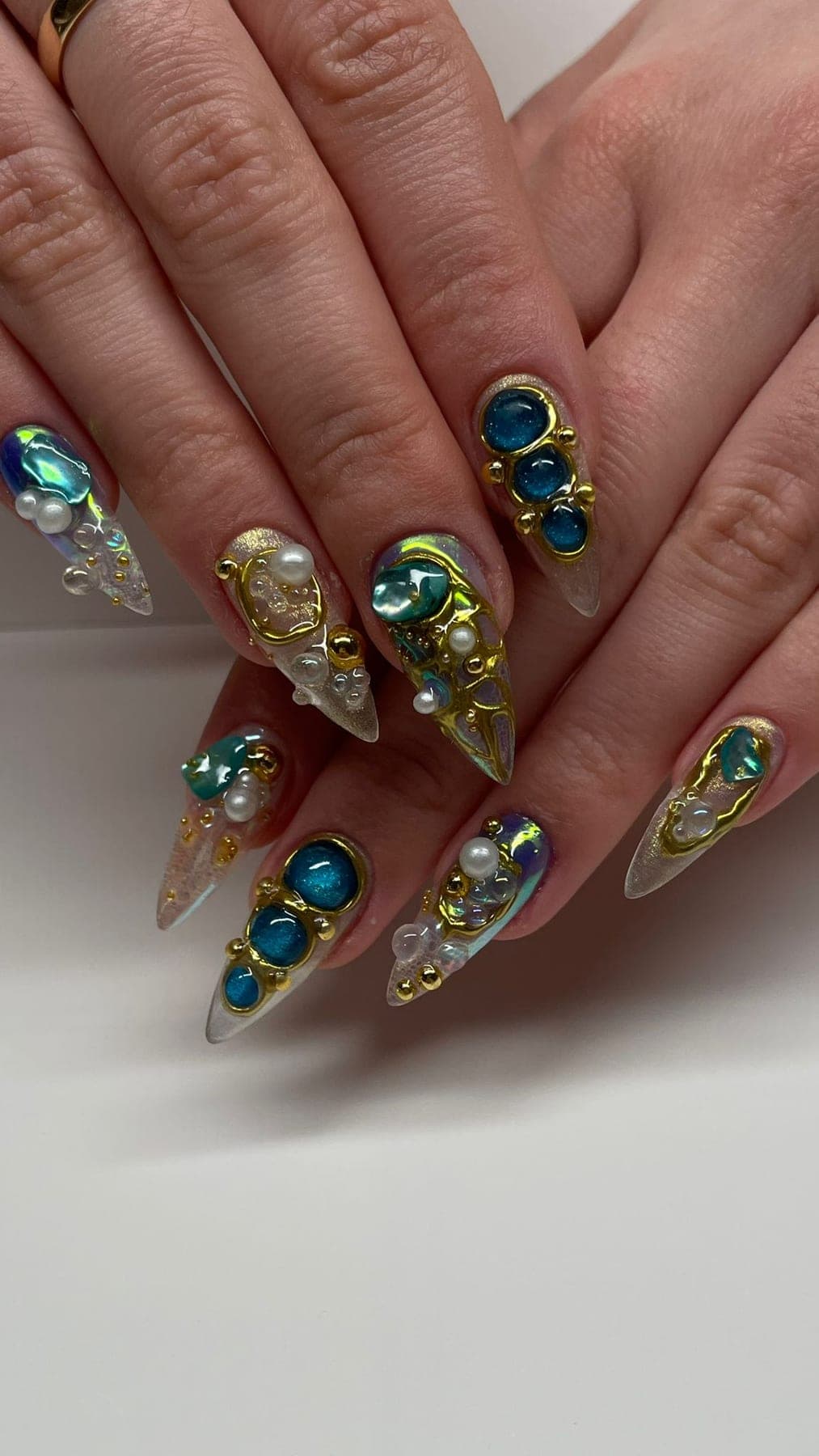 Stiletto nude translucide, strass bleus et perles dorées en cascade.