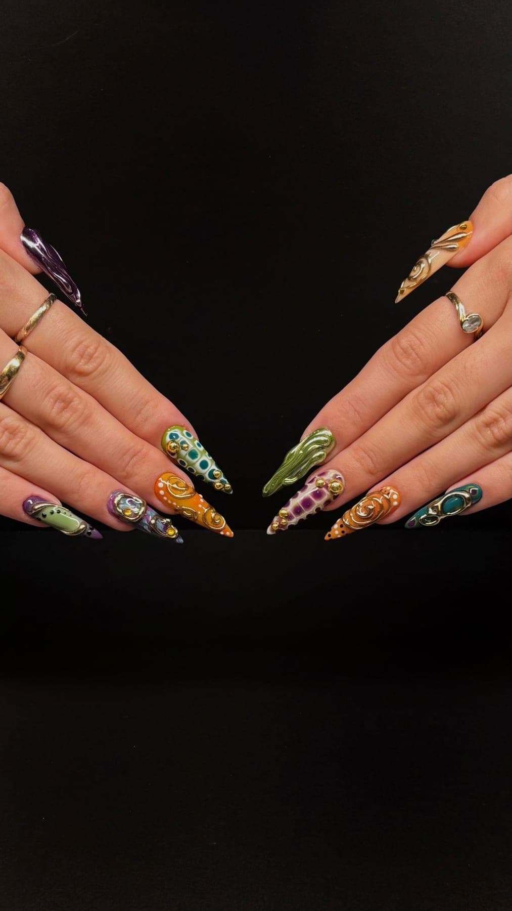 Stiletto multicolore, motifs peints dorés et quelques strass discrets.