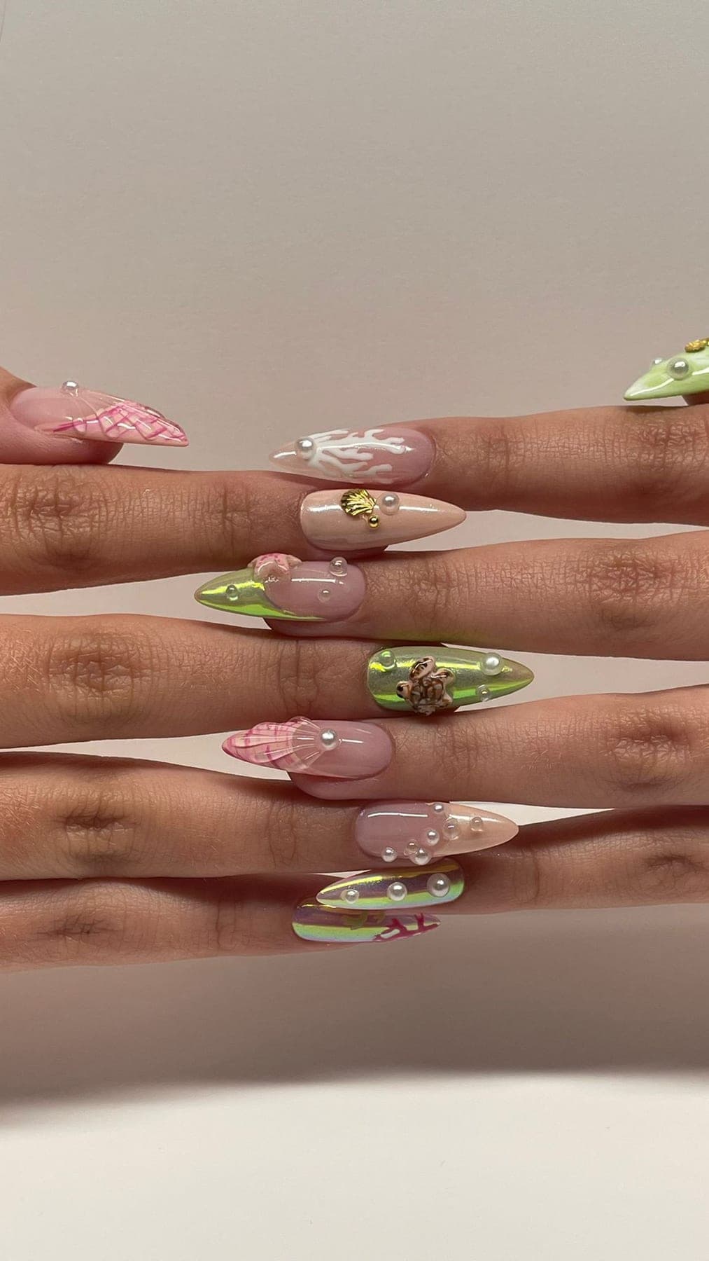 Pose mer et reptile, lézards verts, coquillages roses et perles nacrées.